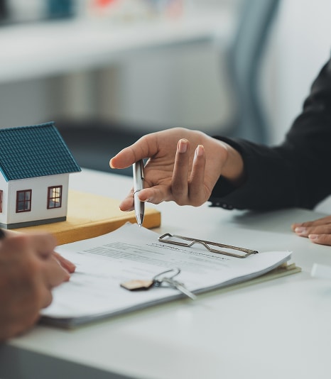 Architecte présentant modèle immeuble neuf de standing Un architecte pointe avec un stylo un modèle réduit d'immeuble moderne gris foncé devant un homme en costume.