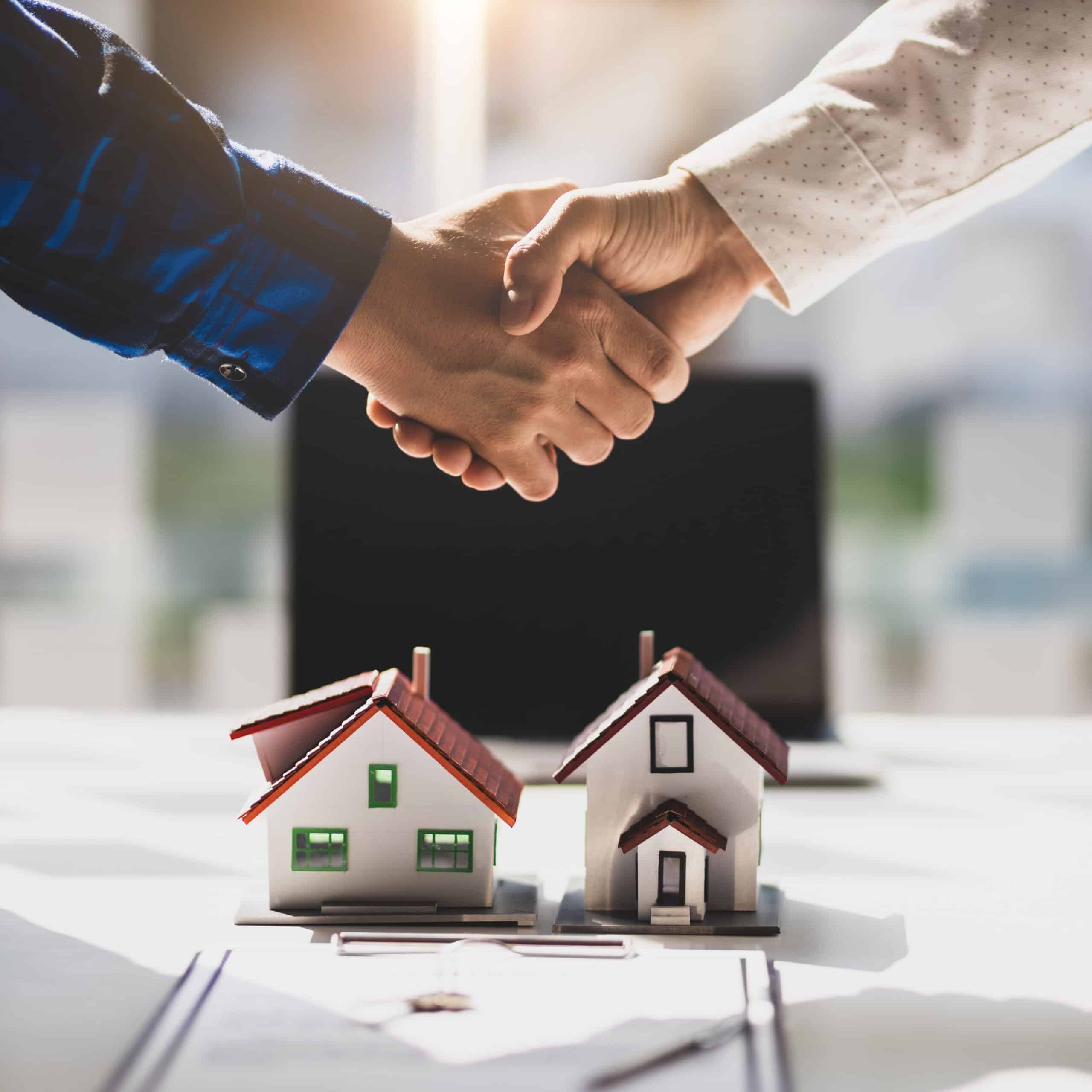 Architecte présentant modèle immeuble neuf de standing Un architecte pointe avec un stylo un modèle réduit d'immeuble moderne gris foncé devant un homme en costume.