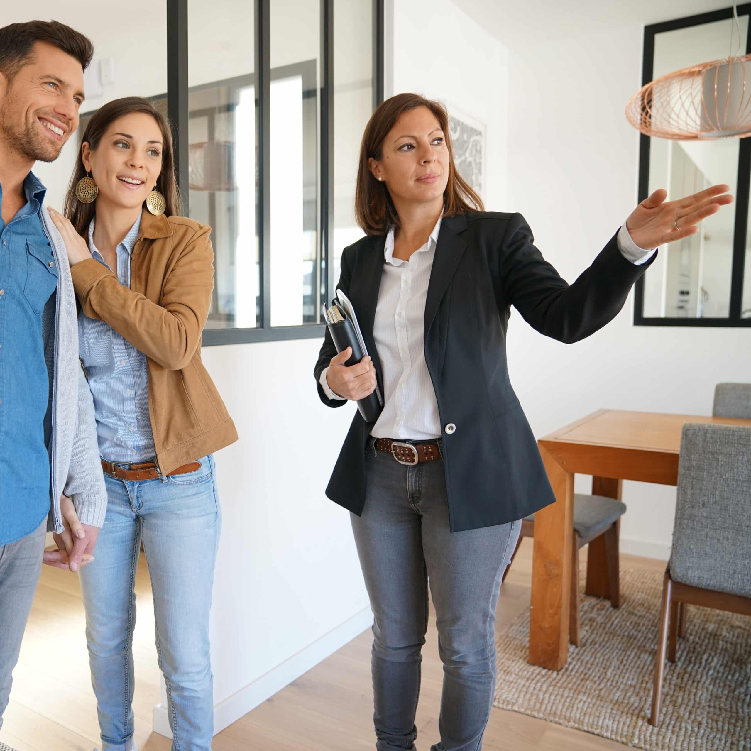 Architecte présentant modèle immeuble neuf de standing Un architecte pointe avec un stylo un modèle réduit d'immeuble moderne gris foncé devant un homme en costume.